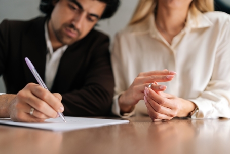 Woman pulling offer her ring while having divorce paper signed