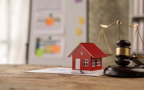 Image of a gavel and wooden house lying on documents
