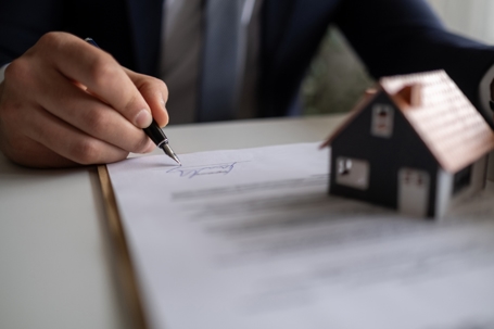 Someone signing a document with a house on top
