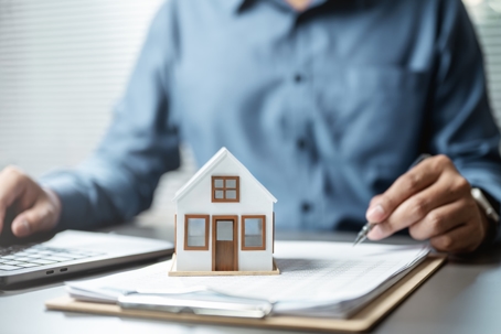 Toy house sitting on a desk with documents
